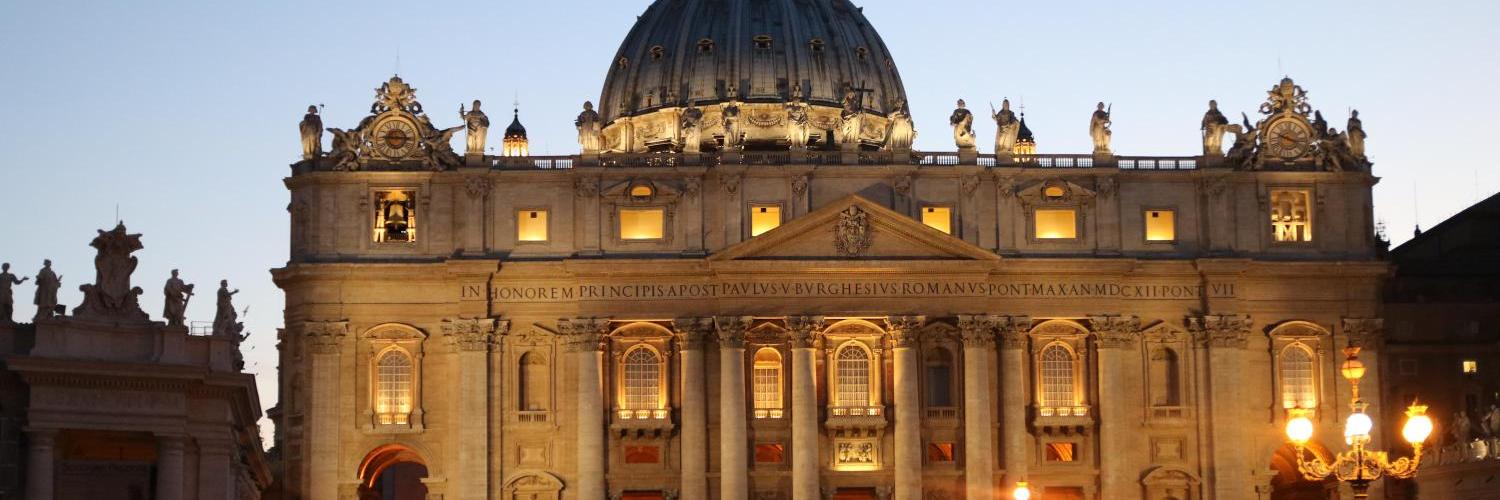 Der Petersdom bei Dämmerung, beleuchtet mit warmem Licht.