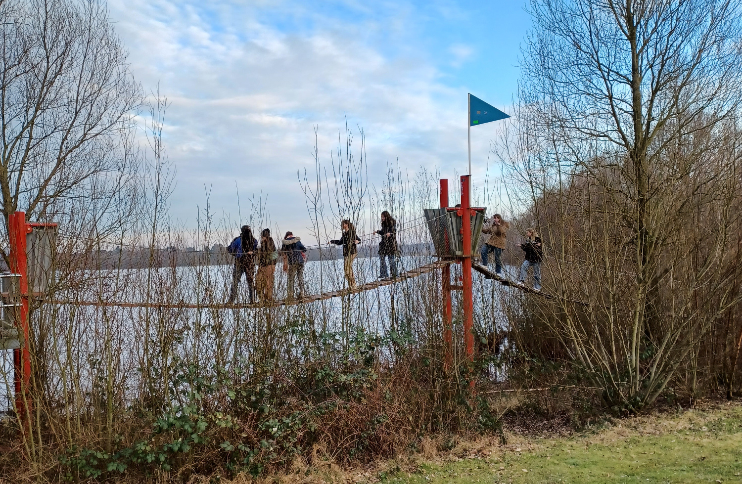 Mehrere Personen auf einer Hängebrücke vor einem See