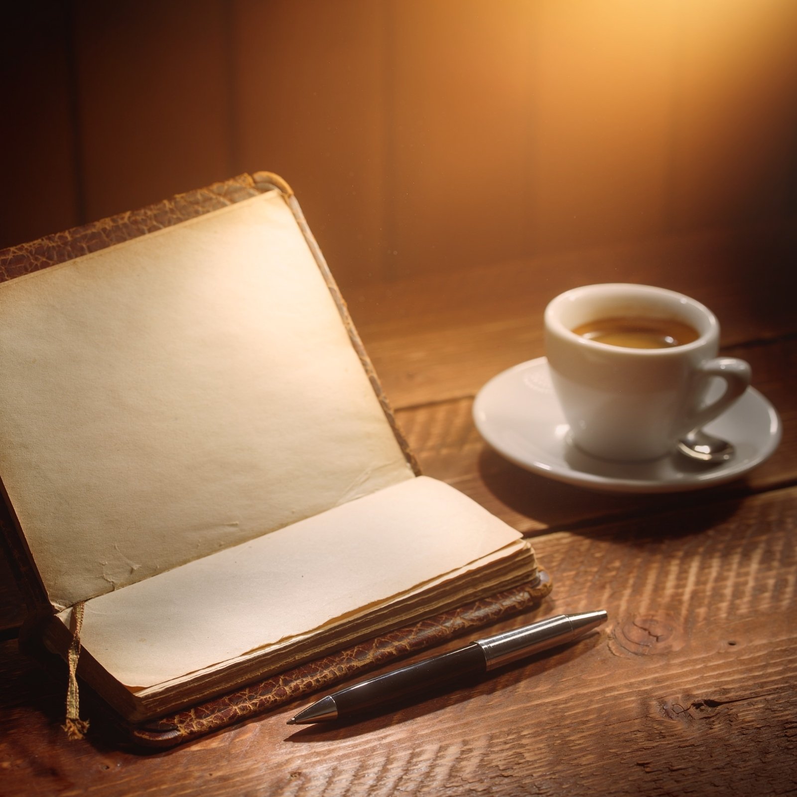 Geöffnetes Notizbuch, Kugelschreiber und Tasse Kaffee auf einem Tisch