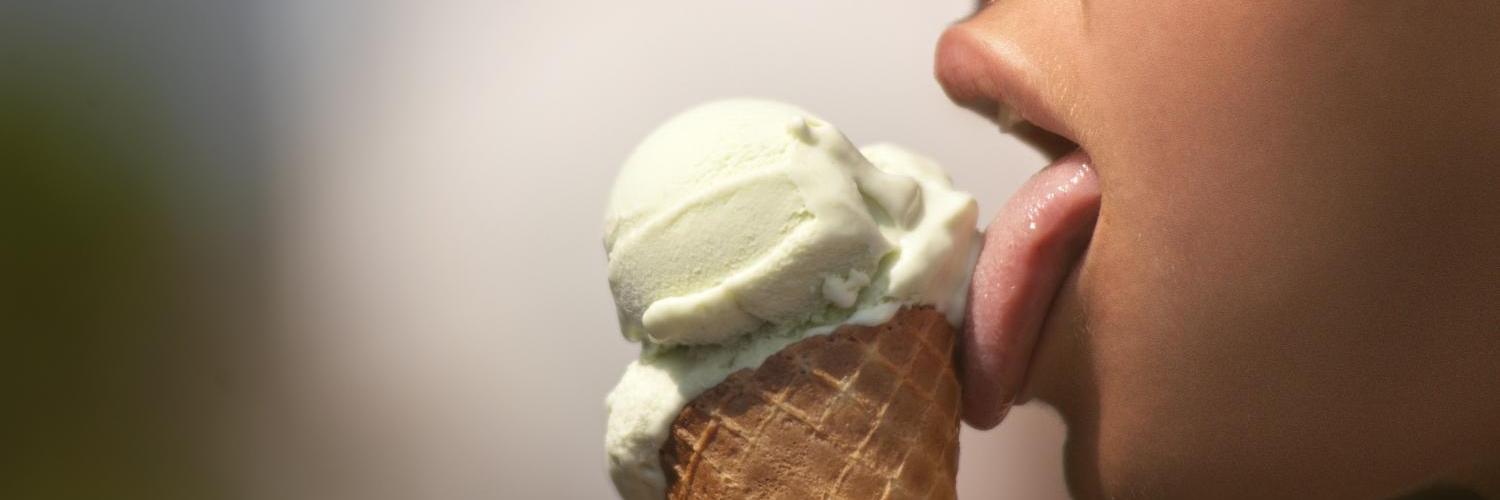 Person leckt an grünem Eis in einer Waffel.