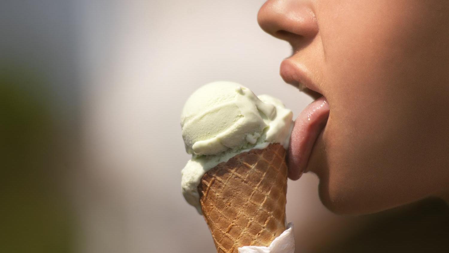 Person leckt an grünem Eis in einer Waffel.