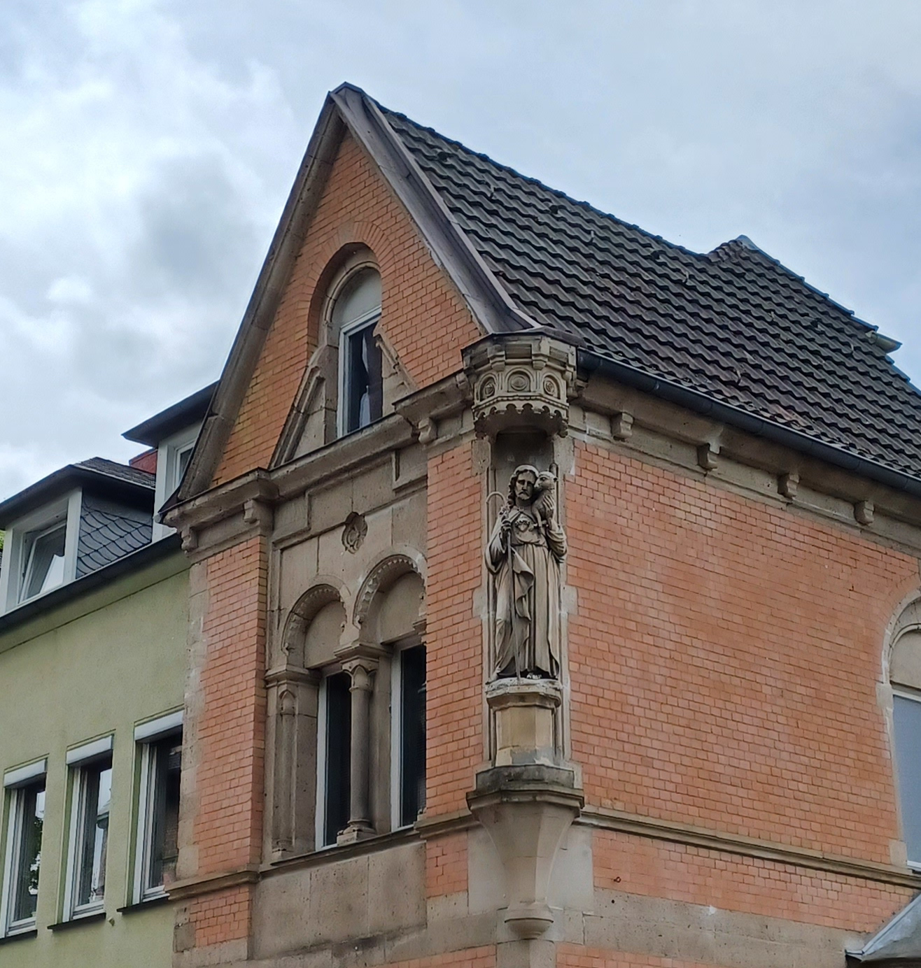 Figur des Guten Hirten an einer Hausecke im ersten Stock des Hauses