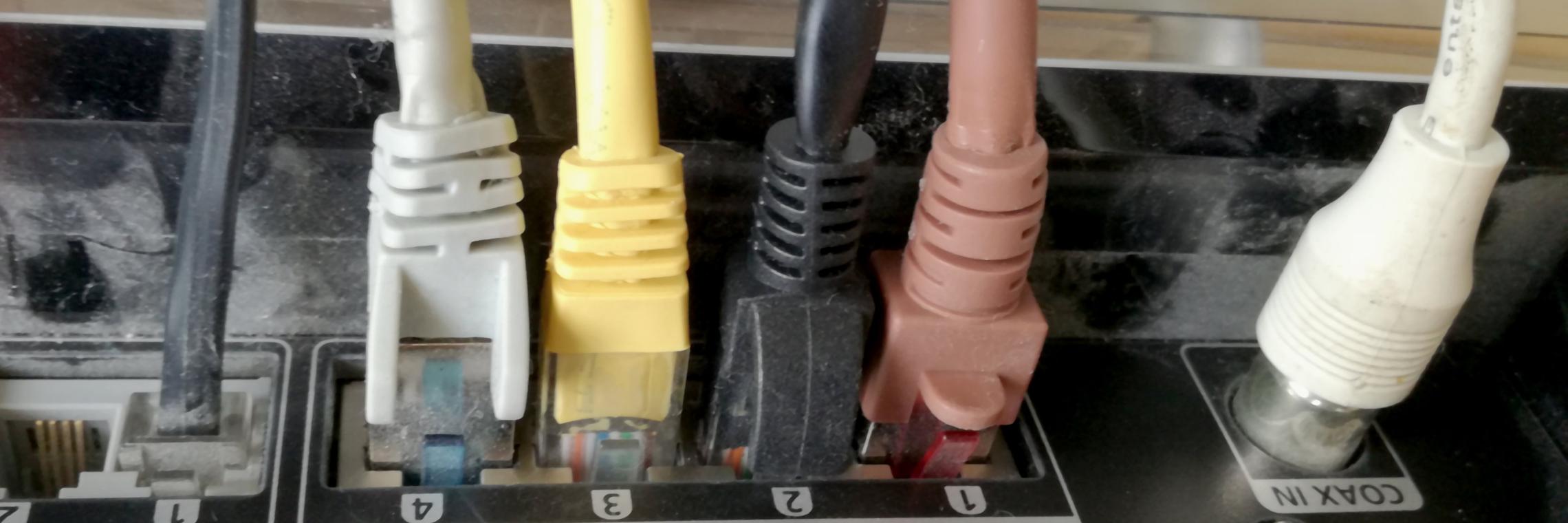 Mehrere farbige Netzwerkkabel sind in einen Router eingesteckt.