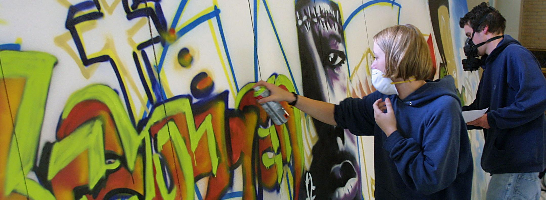 Jugendliche sprayen ein Bild zum Kreuzweg